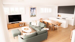 Een moderne woonkamer met een bank, televisie en een eethoek.