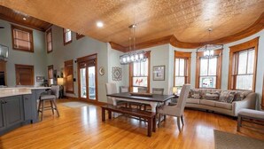 A spacious living area with a wooden floor, a dining table, and a sofa.