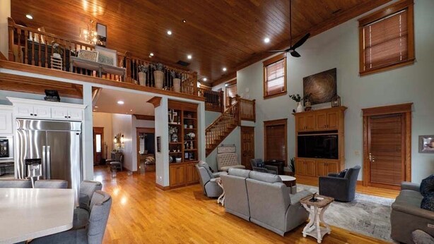 A spacious living area with a wooden ceiling, a staircase, and a kitchen with modern appliances.