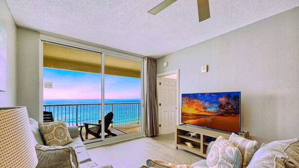 Ein Wohnzimmer mit Balkon, Fernseher und Meerblick.
