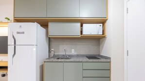A modern kitchen with a built-in refrigerator, microwave, and granite countertop. - OCB - Luxo e Conforto Campo Belo (São Paulo)