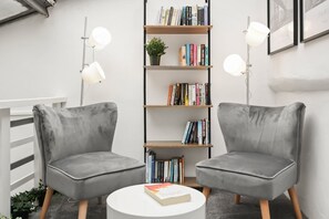 Two grey armchairs facing each other with a bookshelf and a small table between them. - 23A Bevenden Street (Greater London)