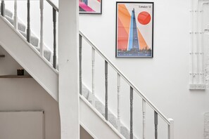 A staircase with a handrail and a wall-mounted picture of London 12. - 23A Bevenden Street (Greater London)