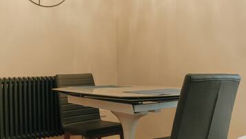 A dining area with a table and chairs, a radiator, and a wall-mounted light fixture.