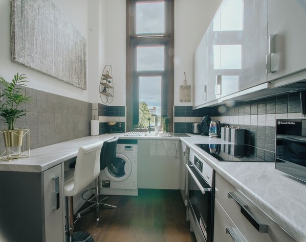 A modern kitchen with a built-in washer and dryer, a large window, and a view of the outdoors. - Outstanding Massive Apartment With Character (Sheffield)