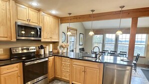 Een moderne keuken met houten kastjes, roestvrijstalen apparatuur en een groot eiland met een spoelbak.