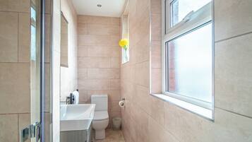 A modern bathroom with a toilet, sink, and window.