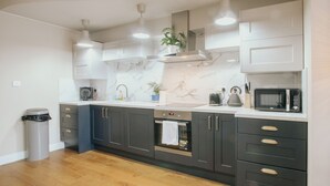A modern kitchen with dark cabinets, a marble backsplash, and stainless steel appliances. - Stunning Quiet Apartment in Historic Building (Sheffield)
