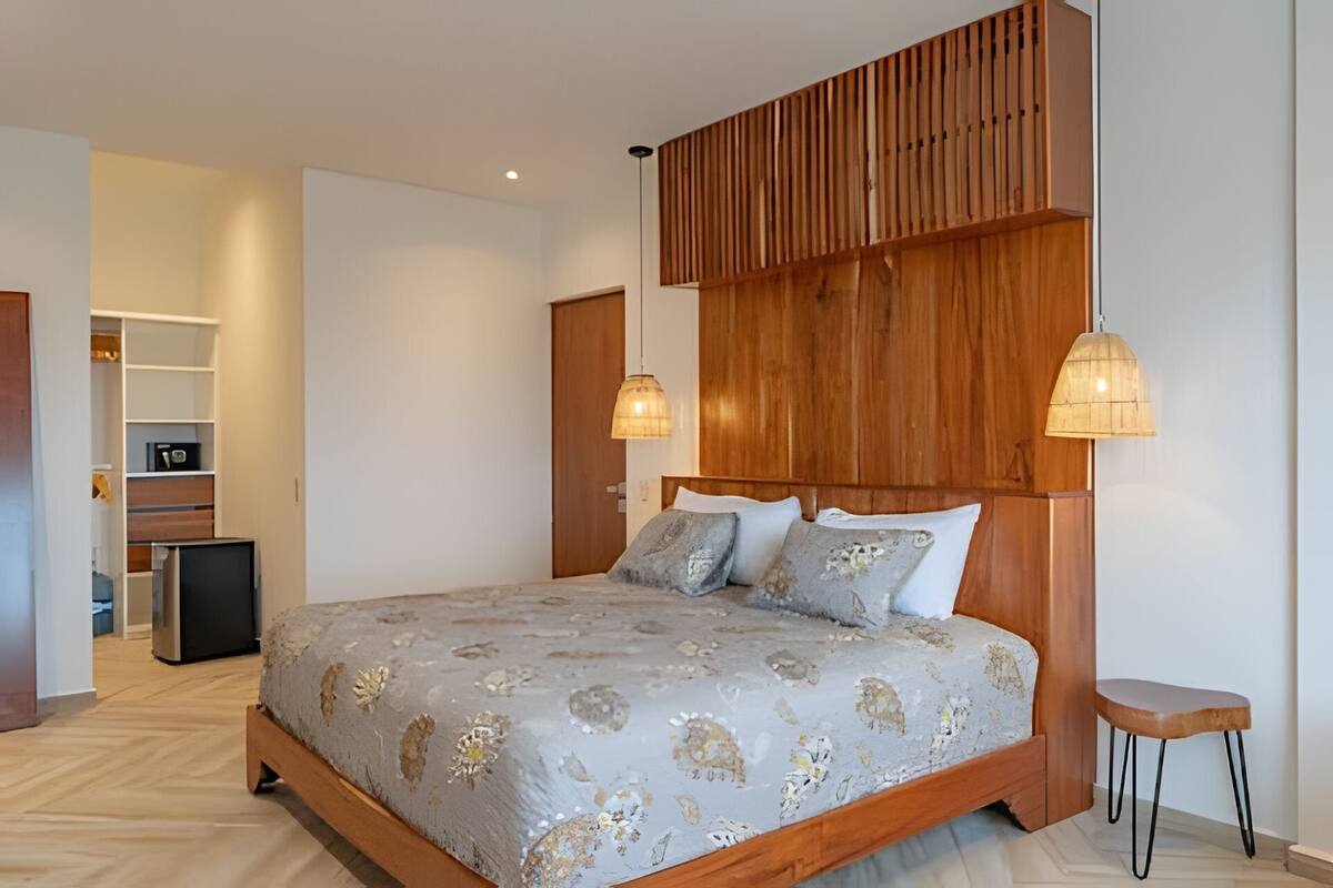 A bedroom with a wooden headboard, a bed with patterned bedding, a bedside table, and a wardrobe.
