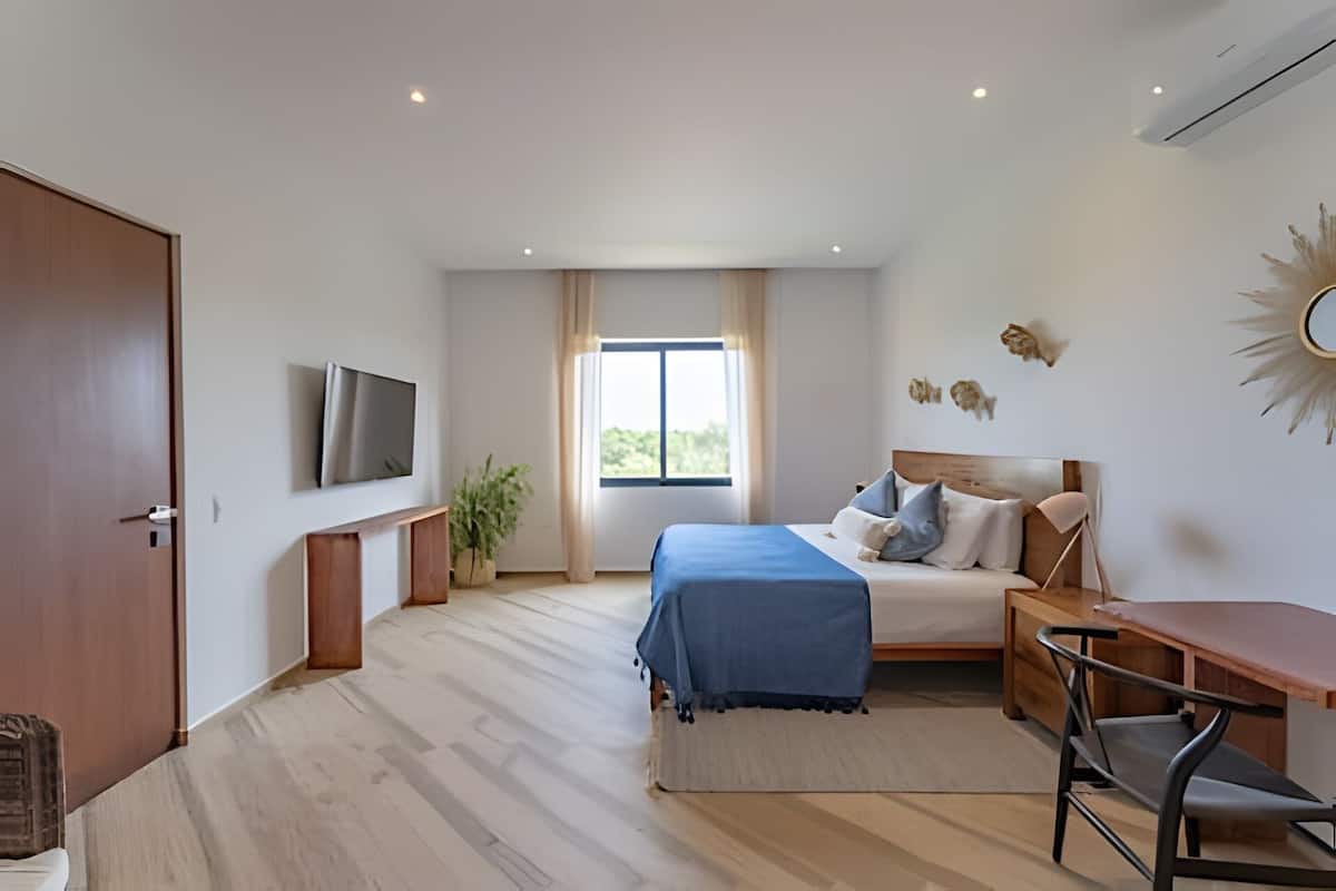A modern bedroom with a large bed, a desk, and a TV.