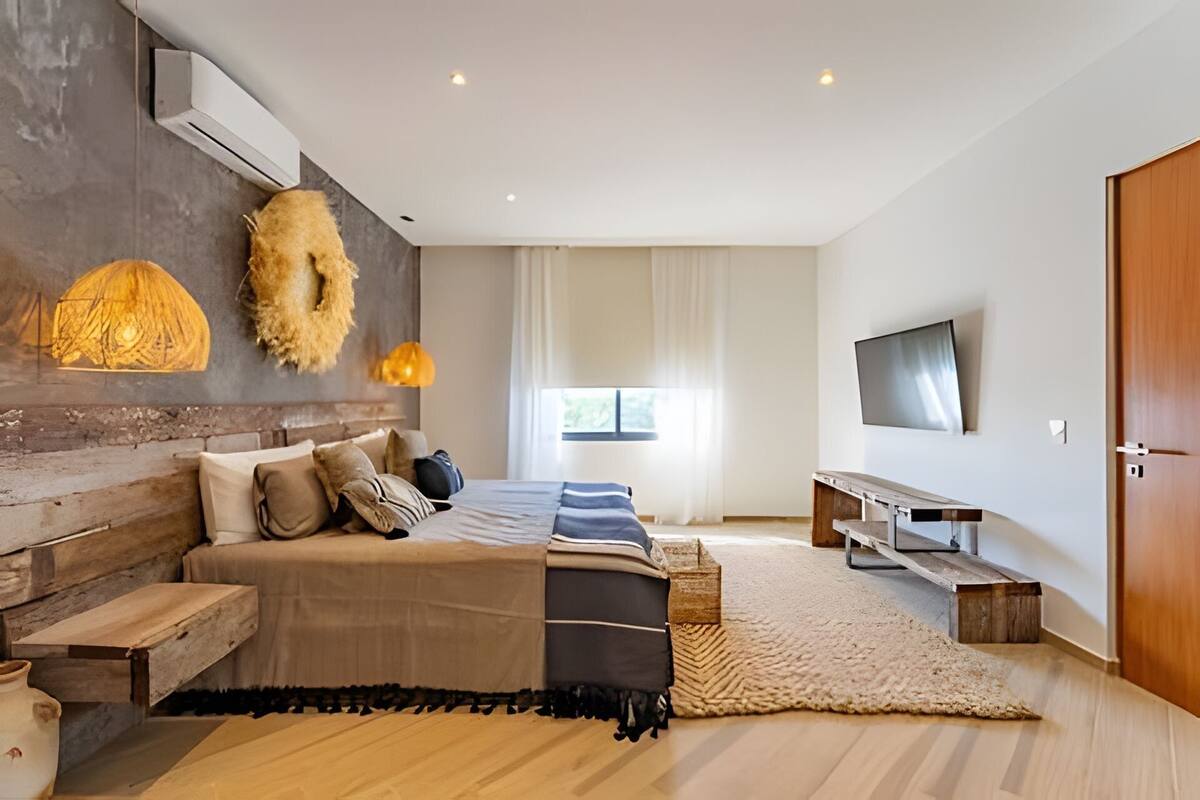 A modern bedroom with a bed, bedside table, and a TV.