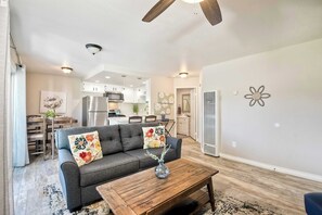 A living room with a sofa, coffee table, and a dining area with chairs and a table. - Silver Surf Getaway - Walk to Beach and Pier (Oceanside)