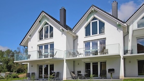 A modern two-story house with a balcony, large windows, and a barbecue grill. - Reihenhaus Hafenflair am Plauer See (Plau am See)