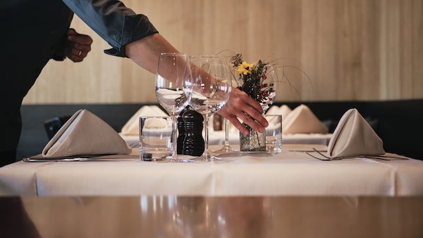 A table set for dining with folded napkins, clear glasses, and a small vase with dried flowers. - Hotel Johann (Lauterach)