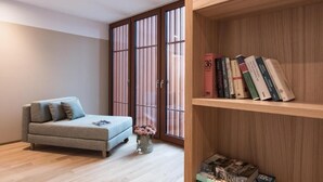 A modern living room with a sofa, a bookshelf, and a sliding door with a view. - Hotel Johann (Lauterach)