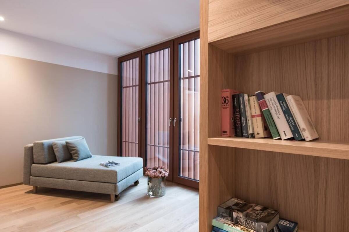 A modern living room with a sofa, a bookshelf, and a sliding door with a view.