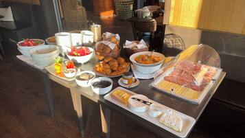 A buffet table with various food items including fruits, pastries, and cheeses.