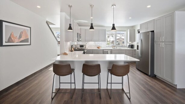A modern kitchen with a central island, bar stools, pendant lighting, and stainless steel appliances. - Modern Mountain Retreat (Silverthorne)