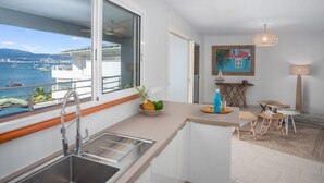 Een moderne keuken met een groot raam, een gootsteen en een eethoek met een tafel en stoelen.