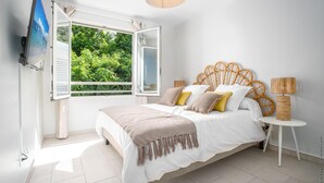 Een slaapkamer met een bed, een raam, een televisie en een lamp.