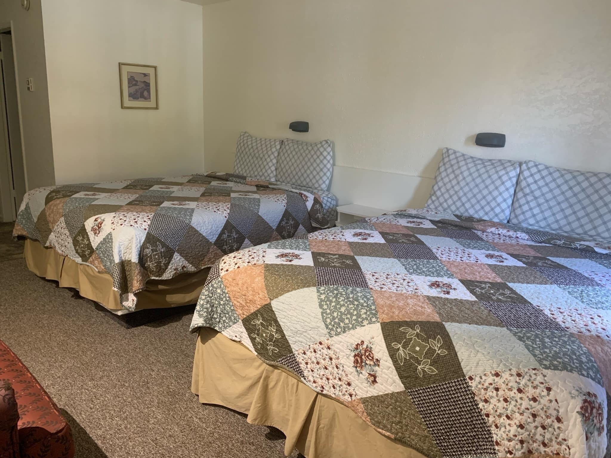 Two single beds with quilts, a small bedside table, and a framed picture on the wall.