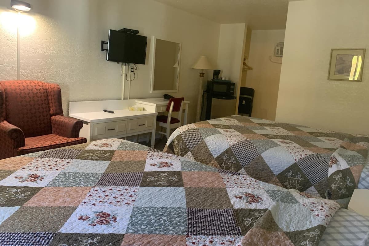 A hotel room with a bed, a desk, a chair, a television, and a microwave.