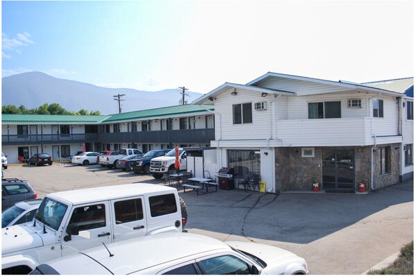 A motel with multiple parking spaces, a barbecue area, and a stone facade office.