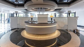 A modern reception area with a central circular counter, marble flooring, and a high ceiling with integrated lighting. - Apartment in Szczecin With Pool and Jacuzzi (Szczecin)