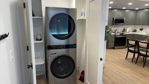 Ein kleiner Hauswirtschaftsraum mit Waschmaschine und Trockner, angrenzend an eine Küche mit modernen Geräten und einem Essbereich.