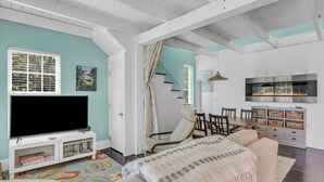 A living room with a TV, sofa, and fireplace. - Secluded Cottage with Beach Access! [Cove Cottage] (Tremont)