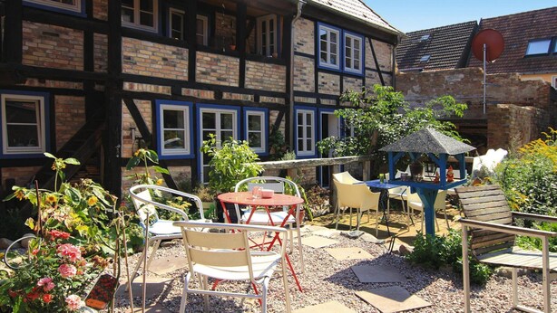 Een traditioneel vakwerkhuis met een tuinpatio, compleet met buitenmeubilair en een prieeltje.