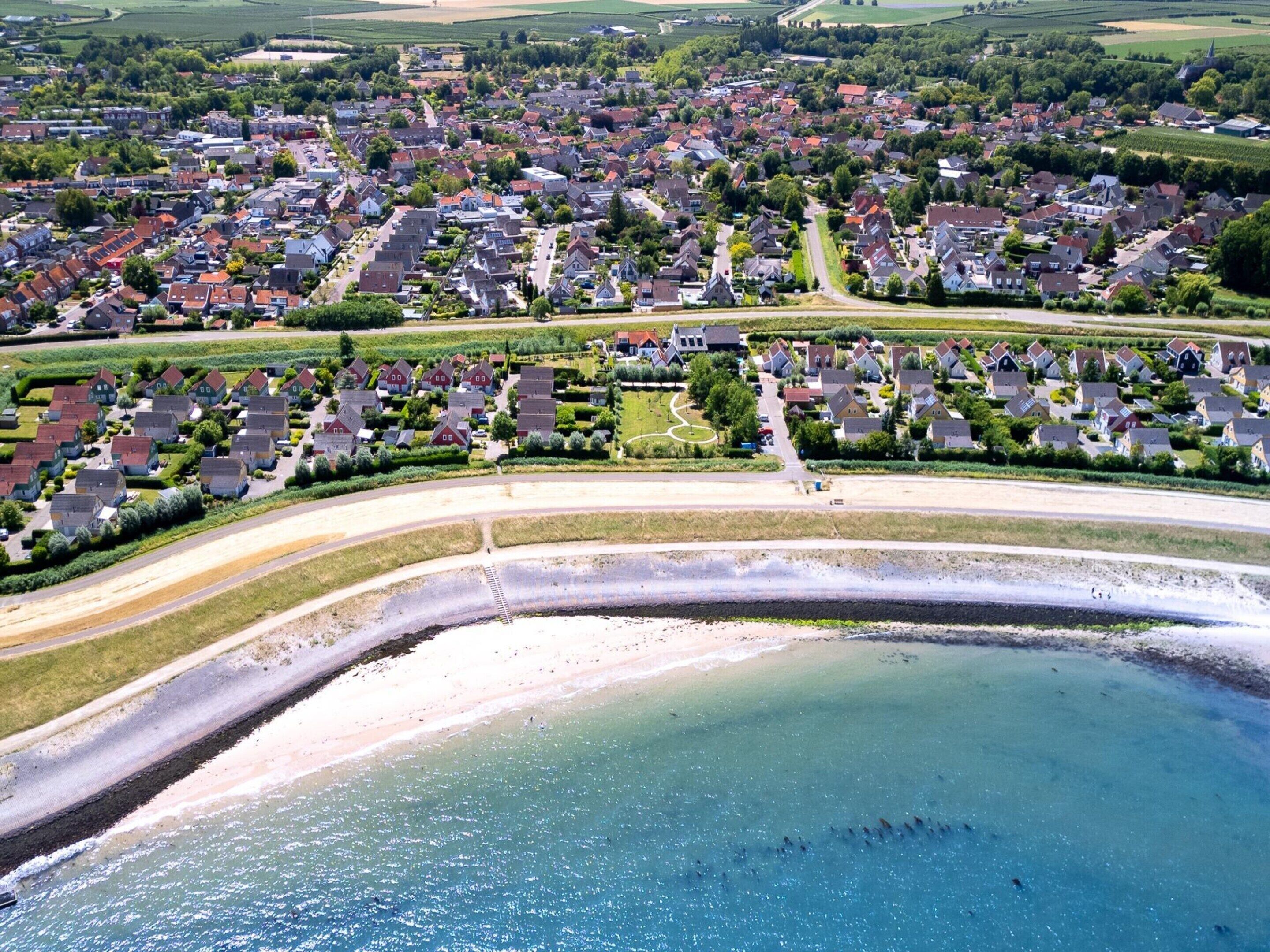 Vista aérea de un pueblo costero con zonas residenciales, una playa y una gran masa de agua.
