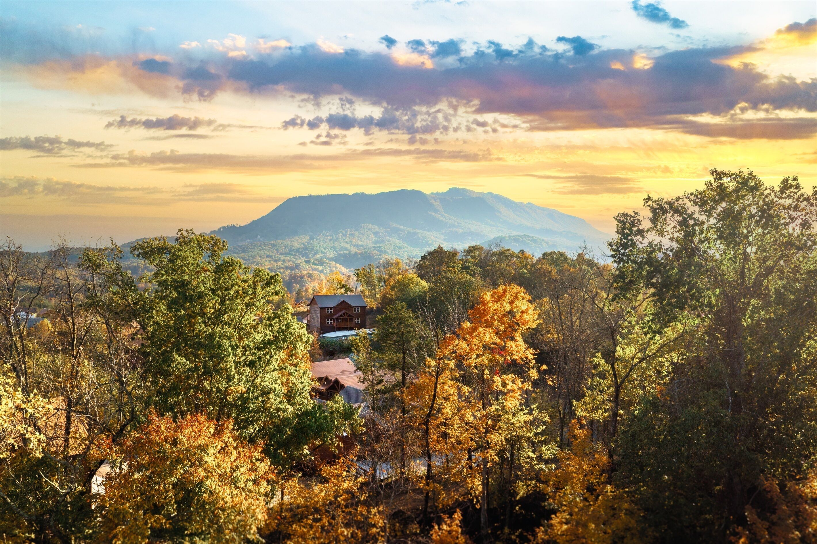 A house surrounded by autumn foliage with a mountain in the background.