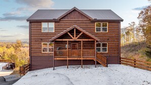 A two-story log cabin with a wooden deck and a covered porch. - Brand New ~ Smoky Mountain Trailhead ~ Panoramic Views & Indoor Pool (Sevierville)