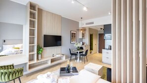 A modern living room with a flat-screen TV, a dining area, and a kitchen. - Apartment in Szczecin With Pool and Sauna (Szczecin)