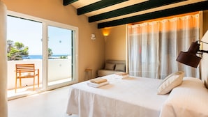 A bedroom with a bed, a chair, and a view of the sea through a sliding door. - 3 Bedroom Villa, Private Pool, 500m to Binisafua Beach (Binisafau)