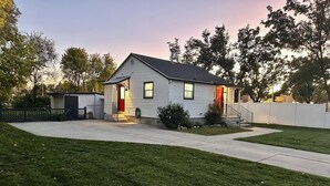 A single-story house with a front porch, a small attached garage, and a well-maintained lawn. - Super Clean, Pet Friendly, Cozy Cottage. (South Salt Lake)