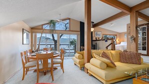 Un vaste espace de vie comprenant une table à manger, un canapé jaune et un pouf rouge.