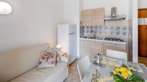 Une cuisine de taille réduite, équipée d’un réfrigérateur, d’une cuisinière et de meubles de rangement en bois.