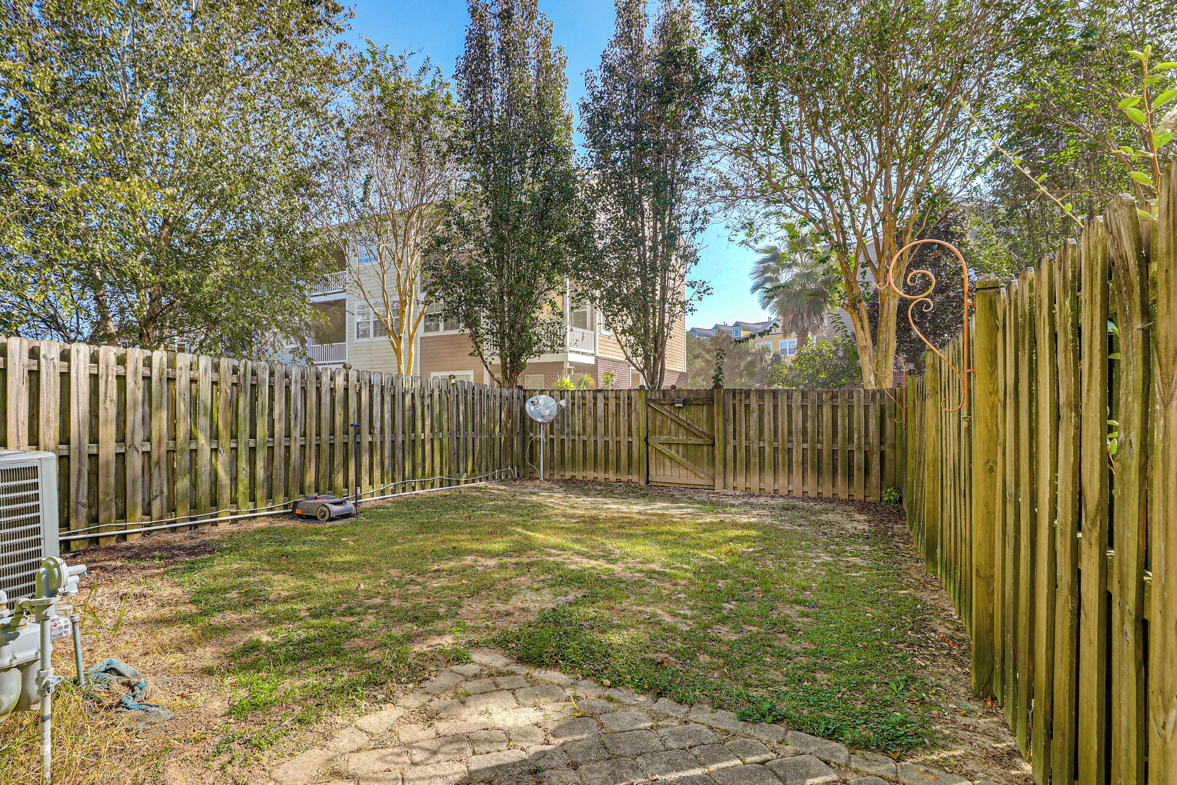 Un jardin avec une clôture en bois, un chemin de pierres et une pelouse.