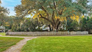 A well-maintained grassy area with a wooden fence and a large tree with hanging moss. - Townhome 3 Mi to Wescott Park & Golf Course! (Ladson)