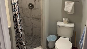 A bathroom with a shower, toilet, and towel rack.