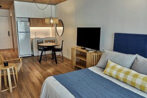 A compact hotel room with a bed, a TV, a small kitchenette, and a dining area. - Studio in Palermo, ideal for couples (Buenos Aires)