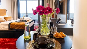 Ett hotellrum med en säng, ett matbord dukat med tallrikar, glas och en vas med blommor.