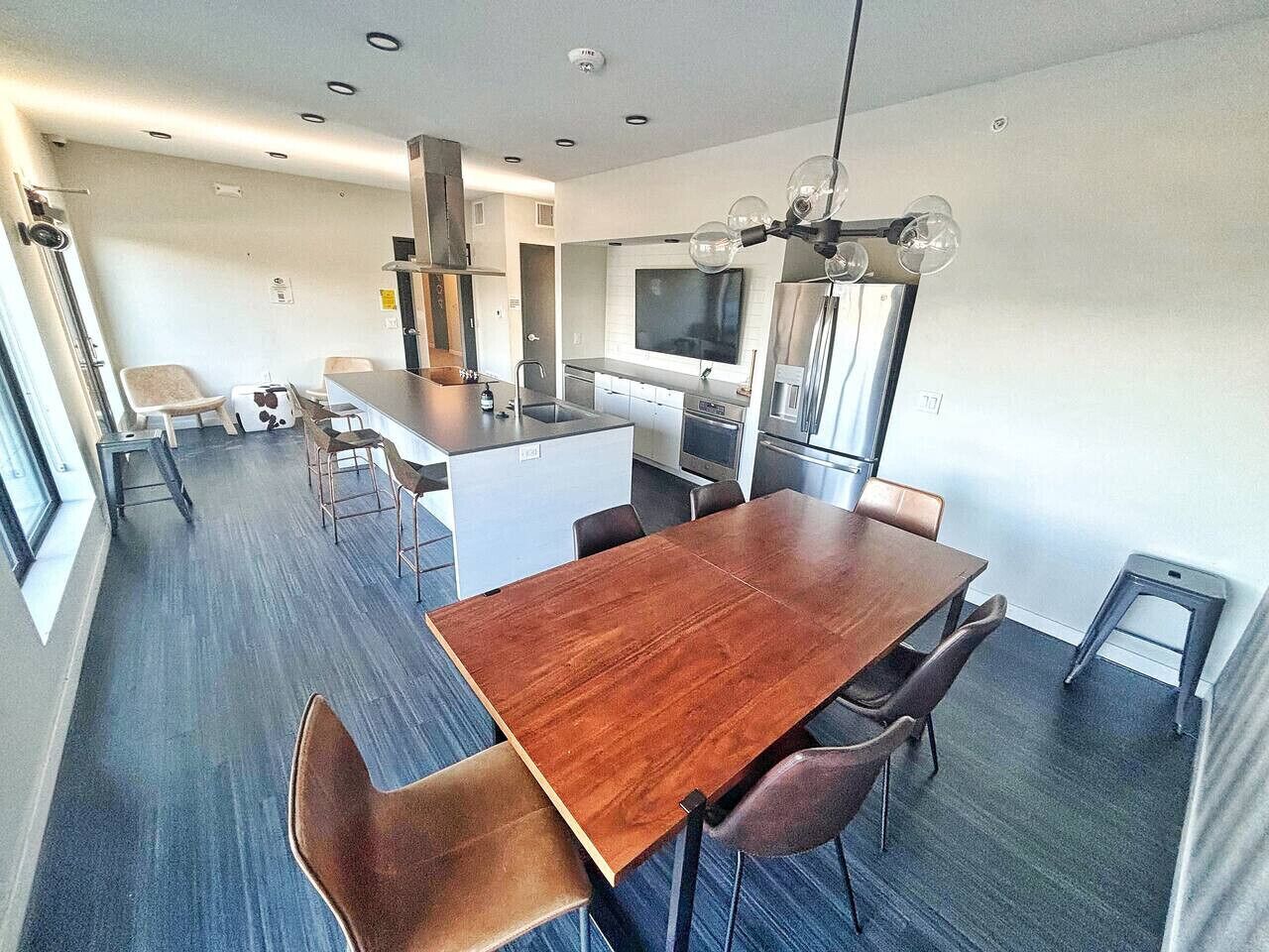 A modern kitchen with a central island, a dining area with a wooden table and chairs, and a large window providing natural light.