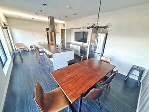 Une cuisine moderne dotée d’un îlot central, d’un coin repas avec une table et des chaises en bois, et d’une grande fenêtre qui laisse entrer la lumière naturelle.