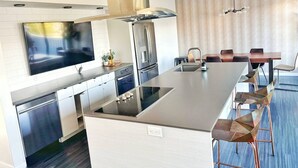 Una cocina moderna con una isla grande, electrodomésticos de acero inoxidable y un televisor de pantalla plana.