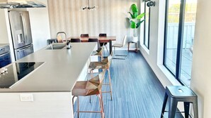 A modern kitchen with a central island, stainless steel appliances, and a large window providing natural light. - Zesty Orange Abode (438) (Des Moines)