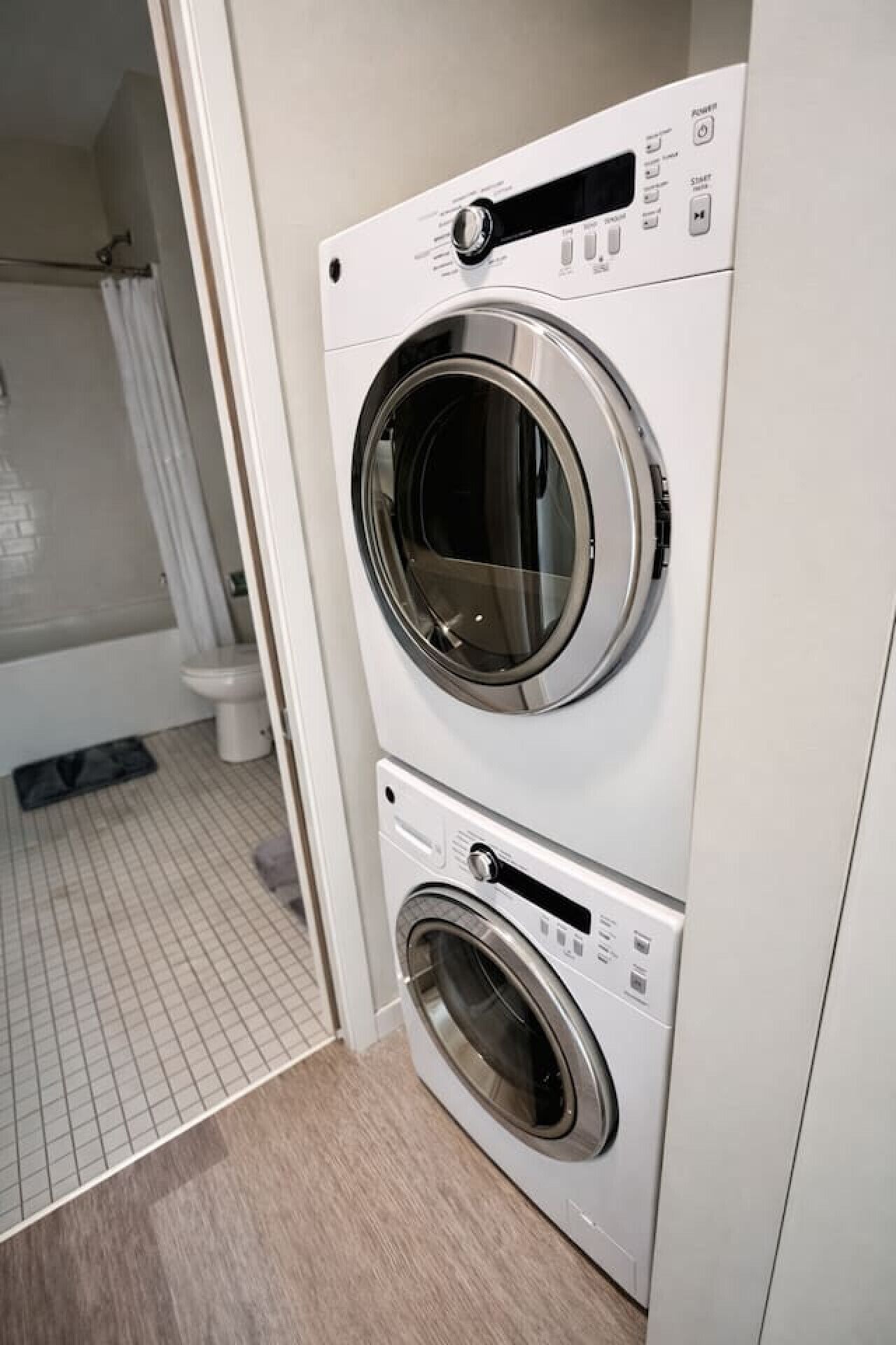 A compact, modern laundry room with two stacked front-loading washing machines.