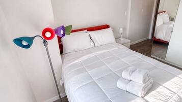 Een hotelkamer met een bed, nachtkastje, lamp en schilderij aan de muur.